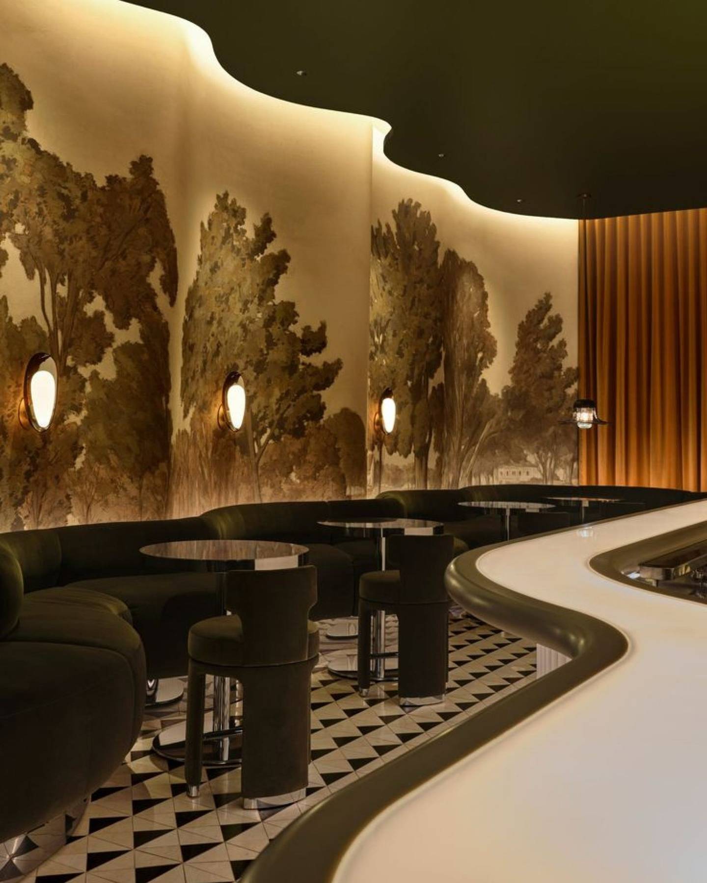 Lounge with green velvet banquettes and a painted forest mural