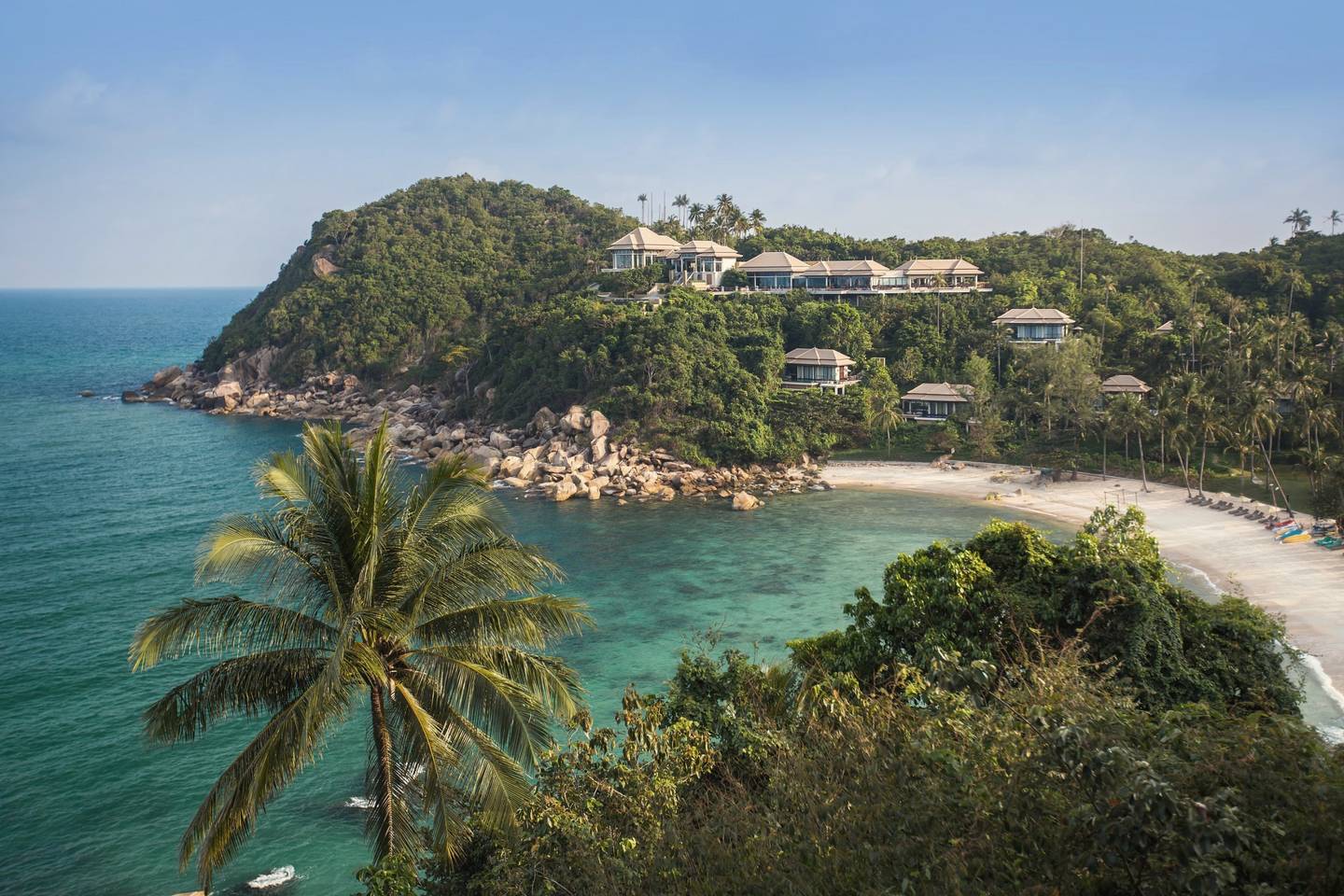 Tropical bay with a white-sand beach below a hillside resort
